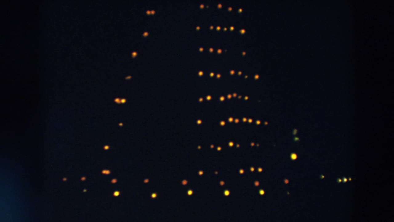 1957 Wheeling, Ohio home-movie frame showing warm lights against a dark sky, suggesting a large Christmas tree display.