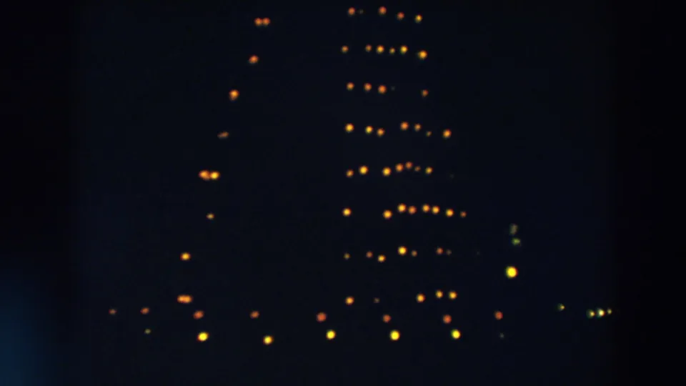 1957 Wheeling, Ohio home-movie frame showing warm lights against a dark sky, suggesting a large Christmas tree display.