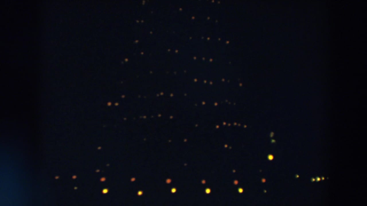 A dark 8mm frame from Wheeling, Ohio, with twinkling lights spread across a tall Christmas tree-like outline.