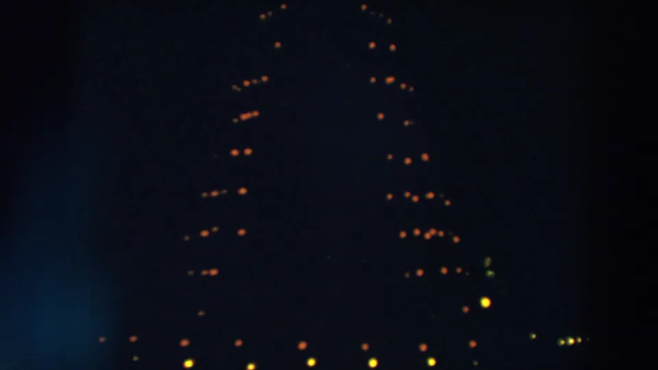 The lower part of the 1957 Wheeling holiday light display appears in soft focus, with warm bulbs against deep night shadows.