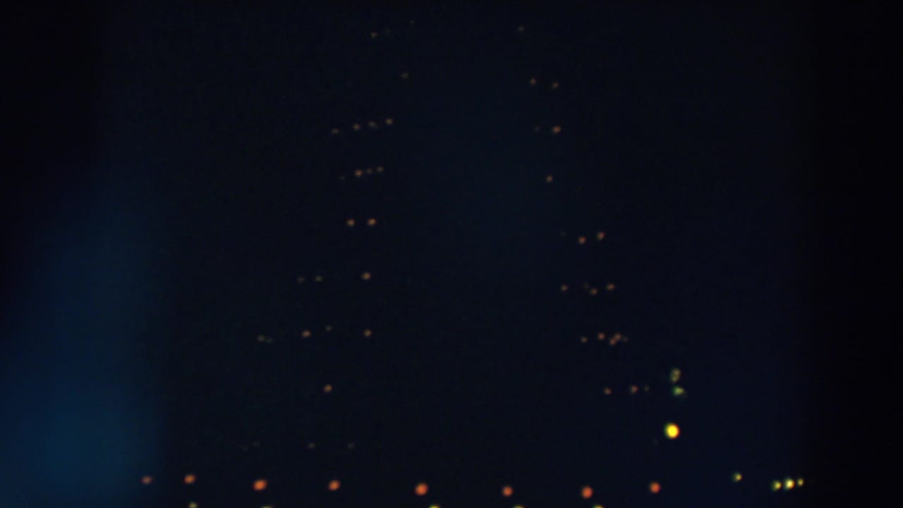 Dark night scene with small orange and yellow lights scattered in the distance.