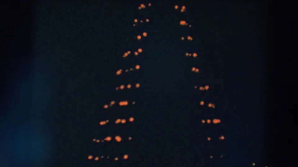 1957 Wheeling, Ohio night footage with two uneven columns of orange lights visible through grain and darkness.