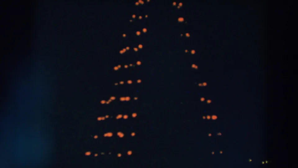 1957 Wheeling, Ohio frame showing clustered orange vertical lights and a few distant yellow points at night.