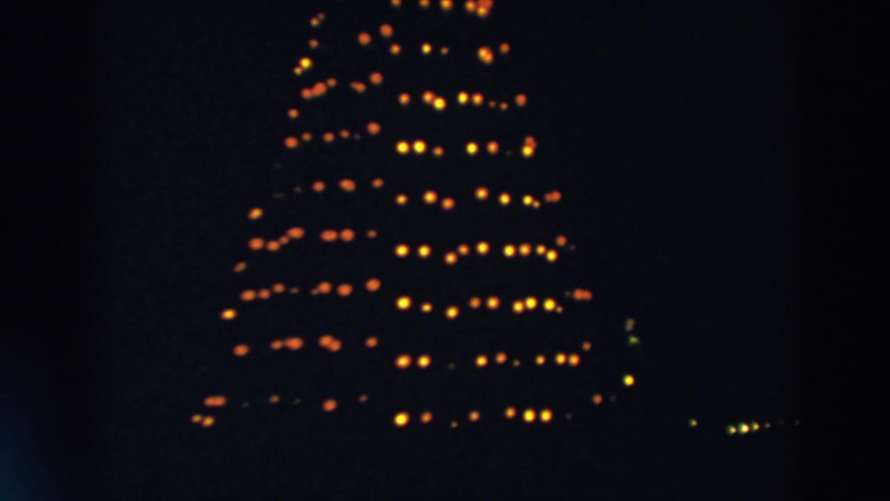 The illuminated Christmas tree remains framed in darkness, with warm bulbs forming rows across the branches in the 1957 Wheeling footage.