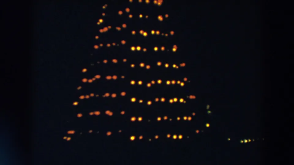The illuminated Christmas tree remains framed in darkness, with warm bulbs forming rows across the branches in the 1957 Wheeling footage.