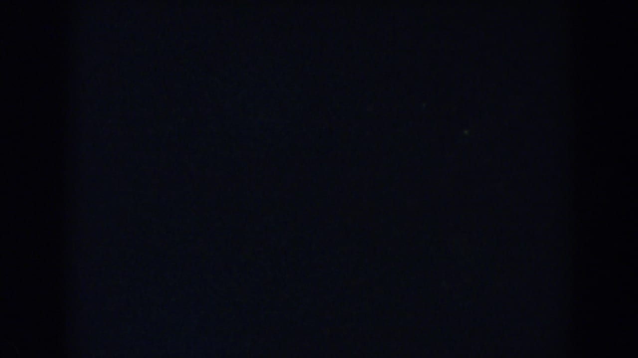 Underexposed 1957 8mm frame from Wheeling, Ohio, showing mostly darkness with faint grain and no clear subject.