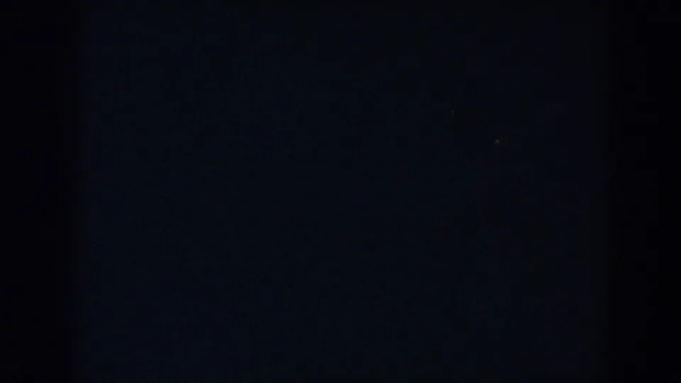 Underexposed 1957 8mm frame from Wheeling, Ohio, showing mostly darkness with faint grain and no clear subject.