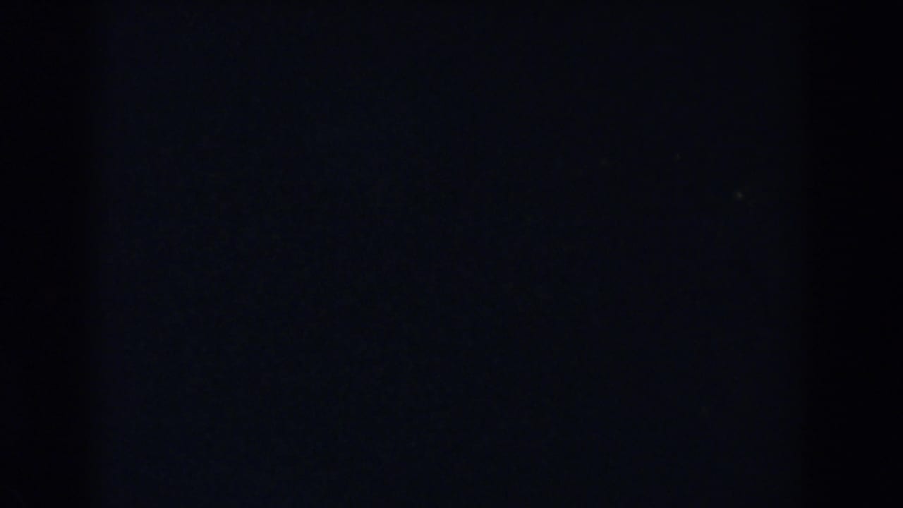 Dark frame with faint grain and a barely visible lower area.