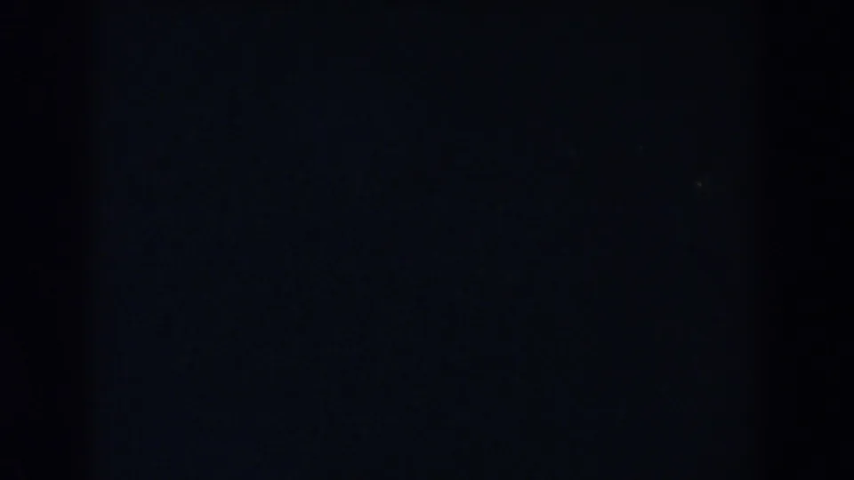 Very dark 8mm frame with faint texture and no clearly identifiable setting or activity visible.