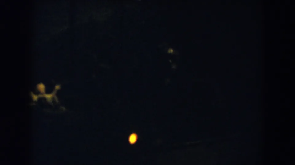 Dark Wheeling, Ohio 8mm frame with a small yellow light and a soft, indistinct human shape near the lower left.