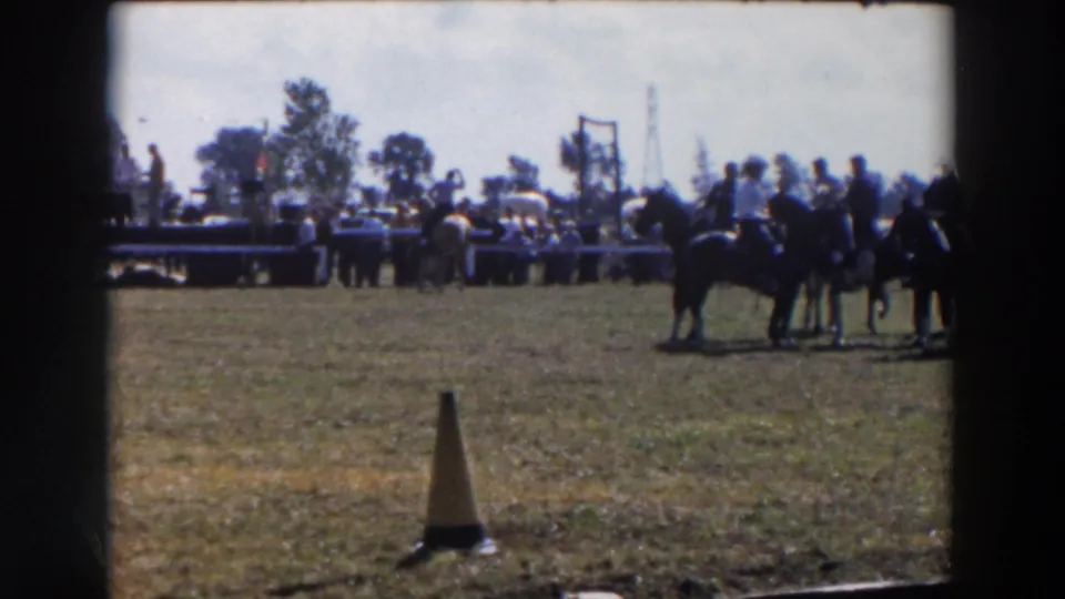 In 1957 Wheeling, Ohio footage, riders on horseback wait in a grassy show ring as spectators and tables sit in the background.