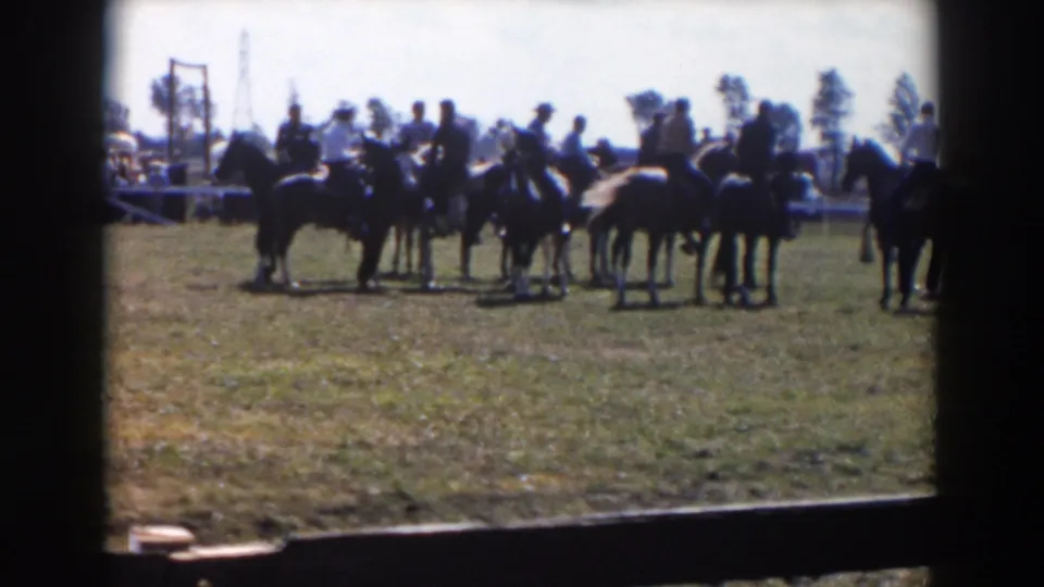 Men on horseback appear to wait or organize on a sunny Wheeling, Ohio field, seen from an amateur 8mm spectator viewpoint.