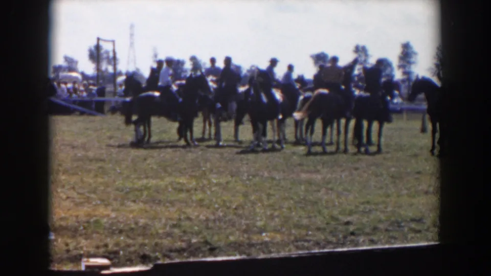 A home-movie frame from the 1957 Wheeling, Ohio clip shows riders and horses grouped near distant spectators, with the film frame border visible.