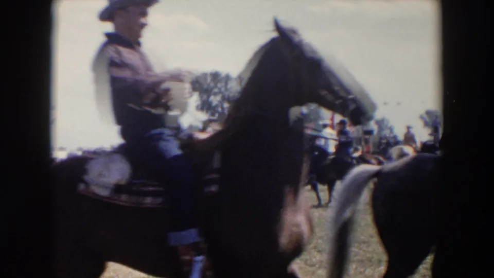 Close 1957 Wheeling, Ohio home-movie view of a mounted rider passing by during the rodeo parade, softened by motion and 8mm focus.