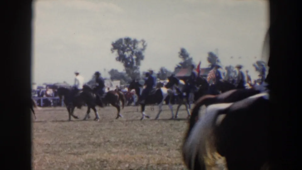 Mounted riders in hats appear near two flags during a 1957 outdoor horseback event in Wheeling, Ohio.
