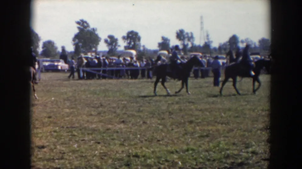 Outdoor horse show frame from the stated 1957 Wheeling, Ohio clip, with mounted riders passing a roped spectator area.
