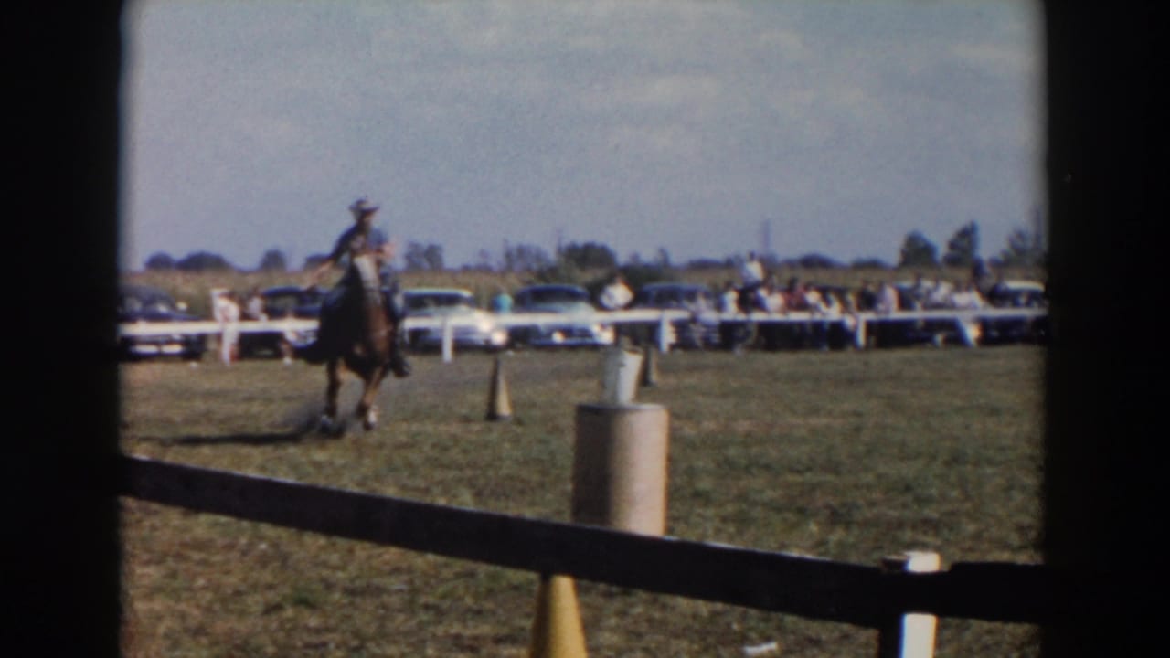 A cowboy-hatted rider on horseback moves through a marked field course at a Wheeling, Ohio fair, with a crowd behind the rail.