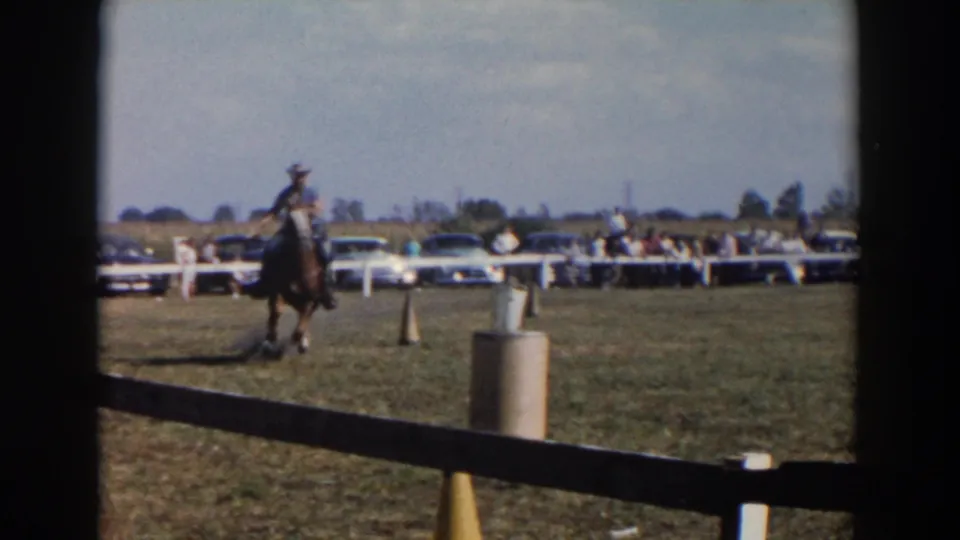 A cowboy-hatted rider on horseback moves through a marked field course at a Wheeling, Ohio fair, with a crowd behind the rail.