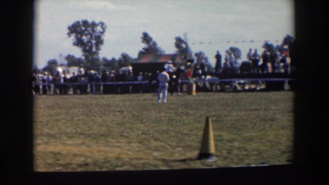 1957 8mm footage from Wheeling, Ohio, showing a rider in light clothing near a yellow cone as spectators watch from behind a barrier.