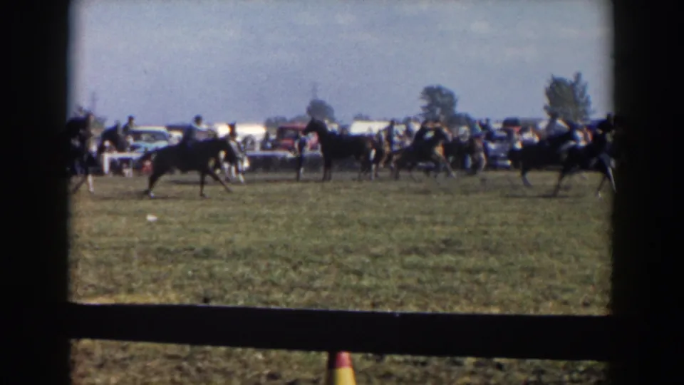 1957 8mm footage from Wheeling, Ohio, showing horseback riders moving across a field with spectators and mid-century cars behind them.