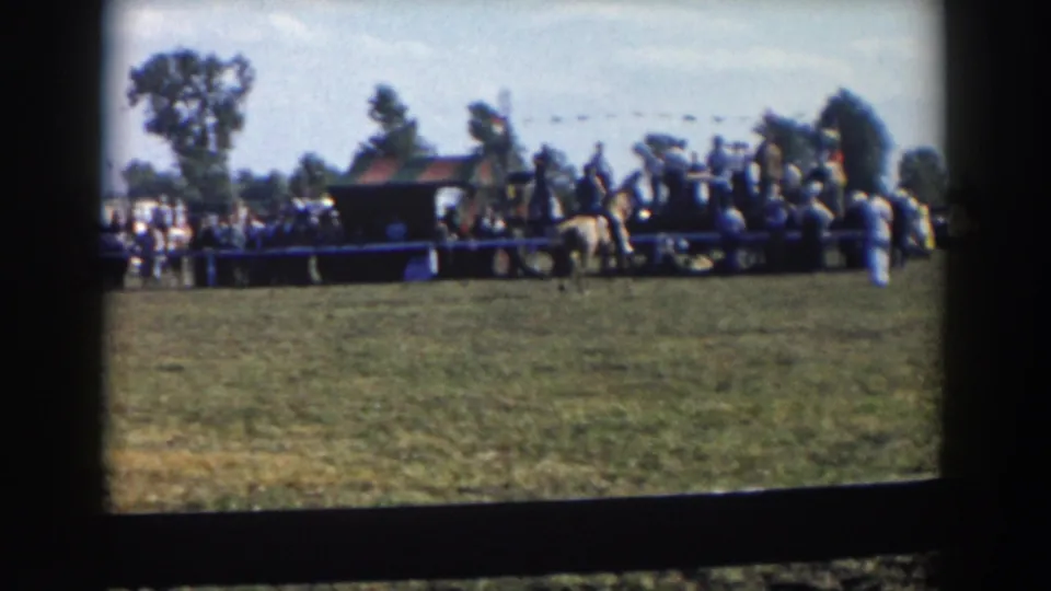 Several riders appear near the crowd at the fairground edge in the supplied 1957 Wheeling, Ohio home-movie footage.