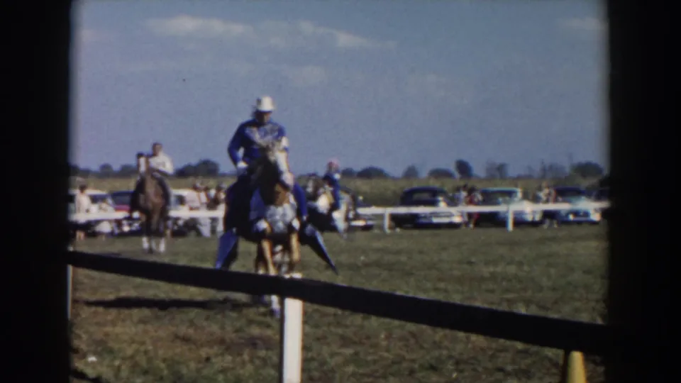 In Wheeling, Ohio, 1957 home-movie footage, a rider in formal attire guides a decorated horse past fencing with parked cars behind.