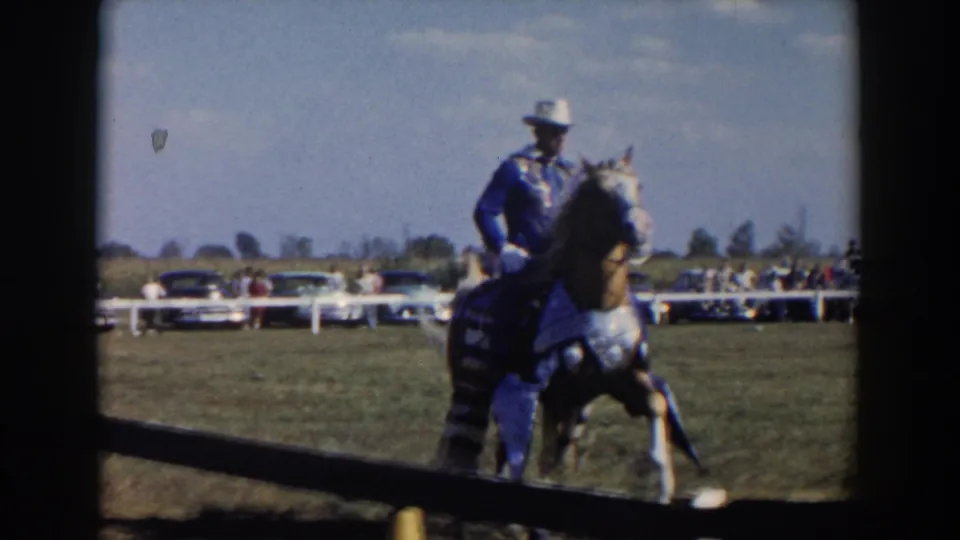 The home-movie frame shows a rider and decorated horse near the foreground fence at the Wheeling, Ohio competition in 1957.