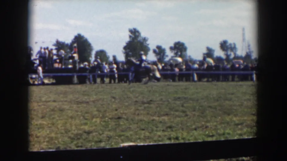 A mounted rider crosses the field near the spectator fence during a 1957 home-movie horse event identified with Wheeling, Ohio.