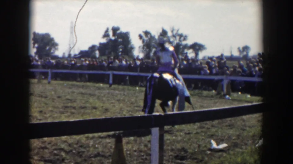 1957 Wheeling, Ohio home-movie frame of a rider farther out in the equestrian field, seen through film-frame borders.