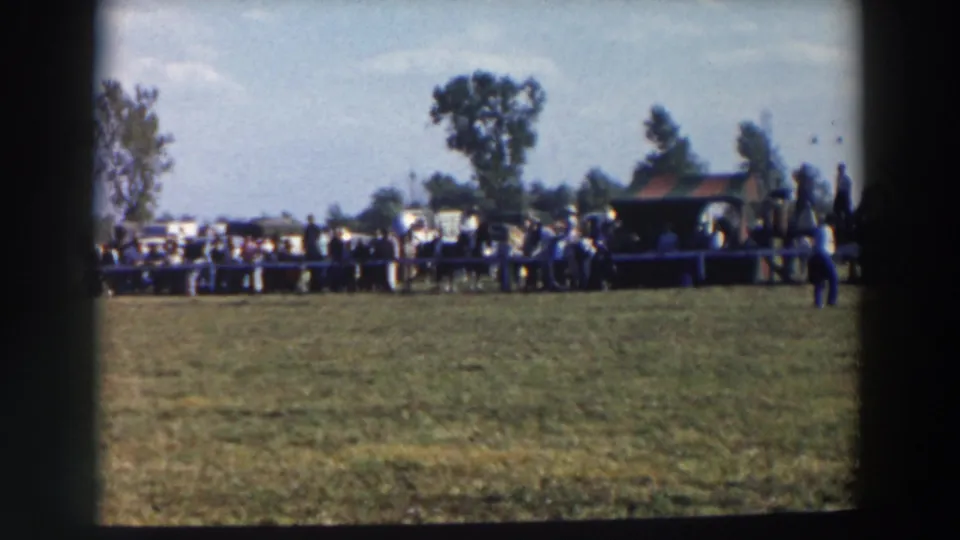 Wide 1957 Wheeling, Ohio view of the equestrian ring, with spectators behind the white fence and a small shelter at the side.