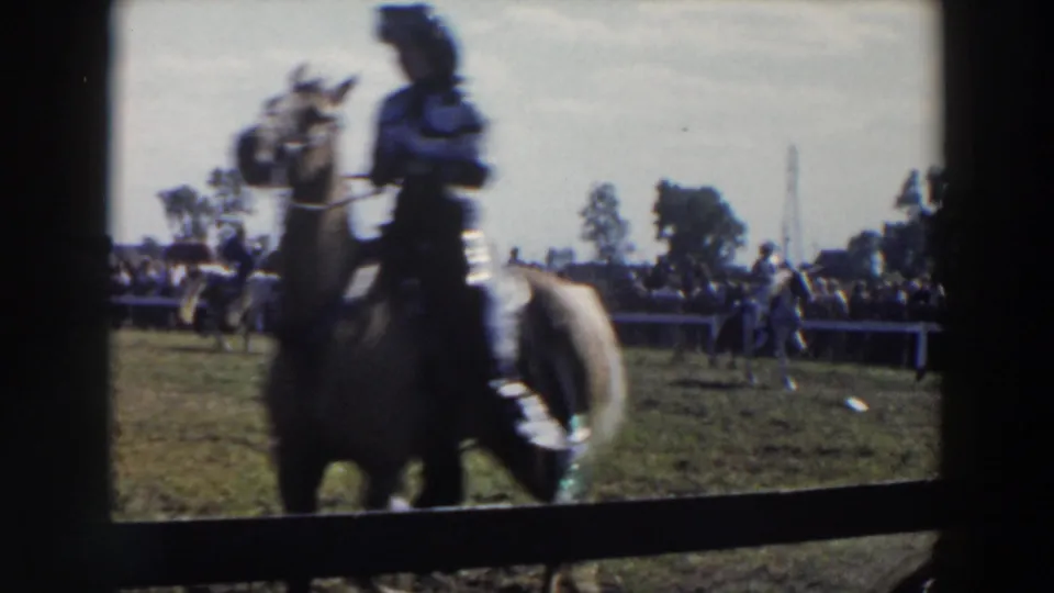 Home-movie frame from the 1957 Wheeling, Ohio event with a rider on a light horse passing close to the camera.
