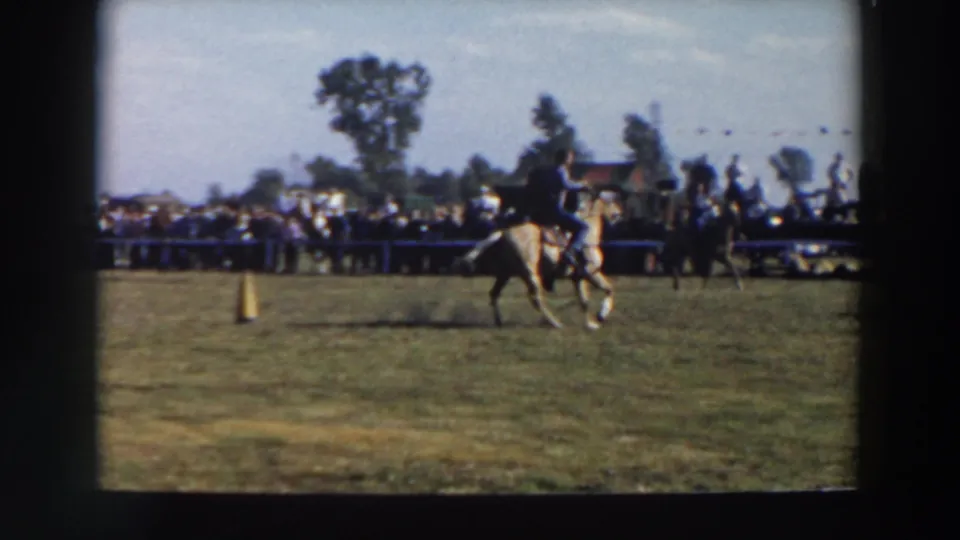 A rider on a light-colored horse crosses the grassy course near a yellow cone during the 1957 Wheeling, Ohio event.