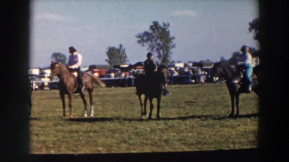 Horseback riders wait in a loose row at the 1957 Wheeling, Ohio equestrian gathering, seen from a handheld 8mm perspective.