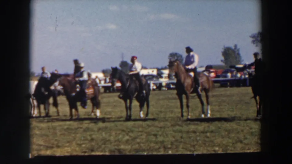 Mounted riders in cowboy hats appear to wait or organize on a grassy field at a 1957 Wheeling, Ohio horse event.