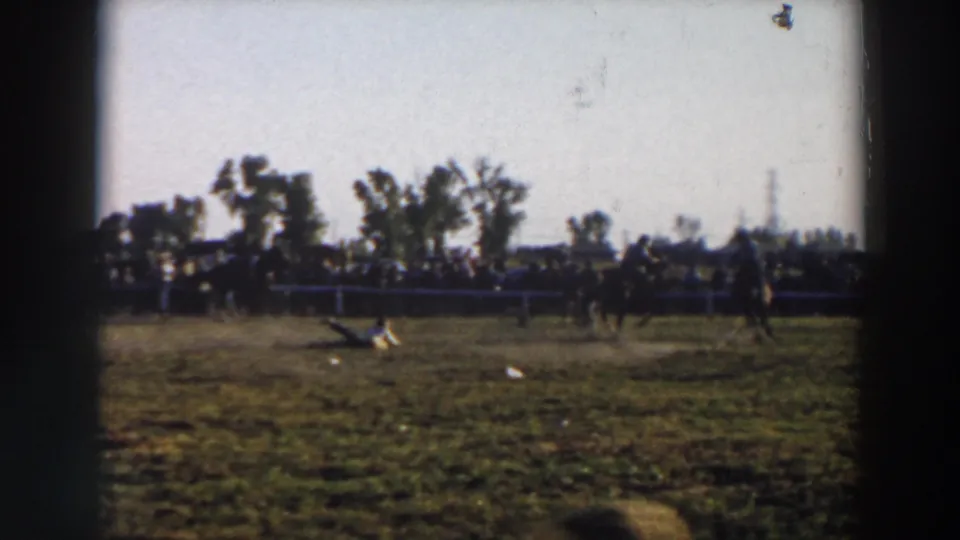 Wide home-movie view of a rider crossing the Wheeling horse show field with spectators behind fencing.