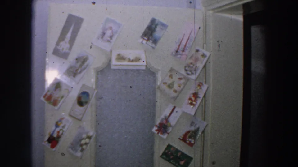 Soft 1958 Italy 8mm view of a decorated interior door with multiple holiday-style postcards surrounding the central panel.