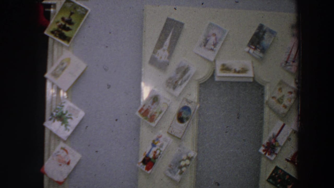 1958 Italian home interior with Christmas cards displayed around a doorway and a closed door in soft 8mm color.