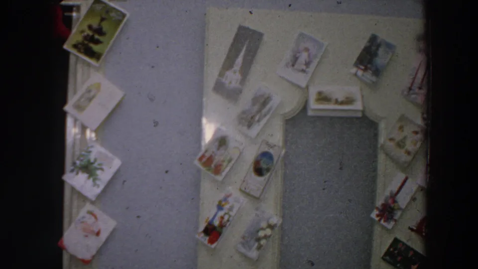 1958 Italian home interior with Christmas cards displayed around a doorway and a closed door in soft 8mm color.