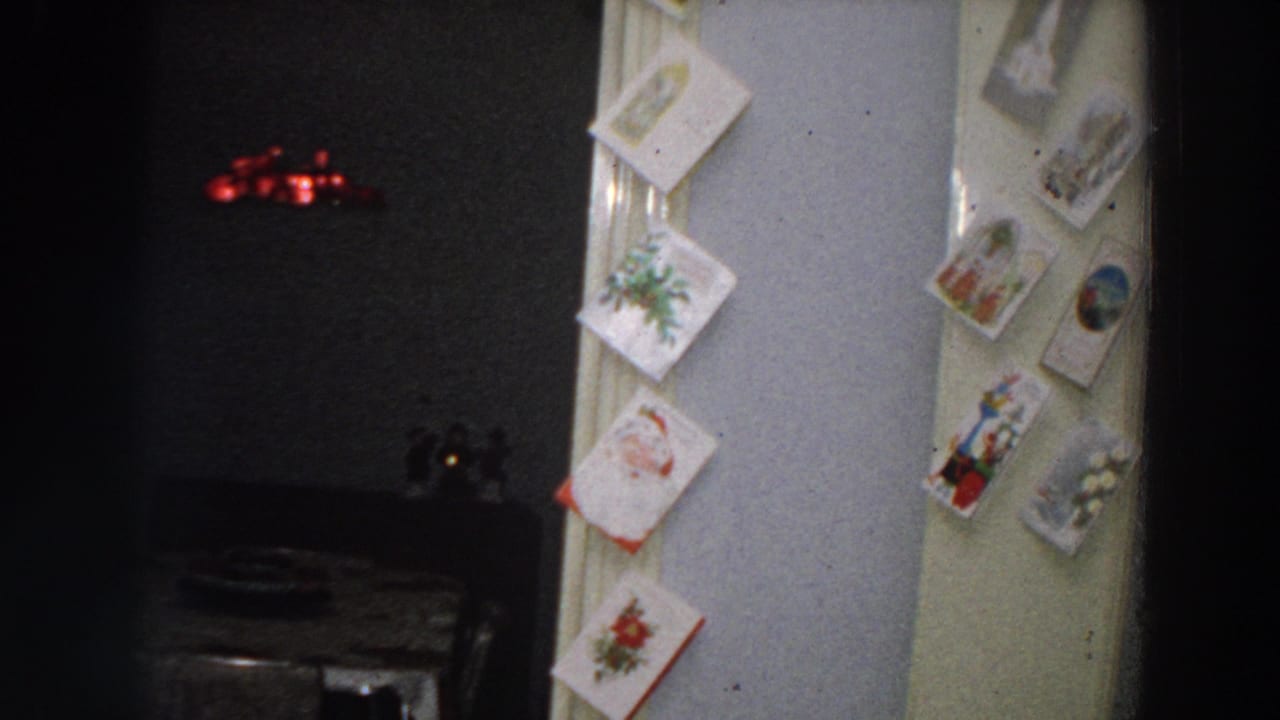 Dim dining room seen through a doorway with Christmas cards tacked along the frame.