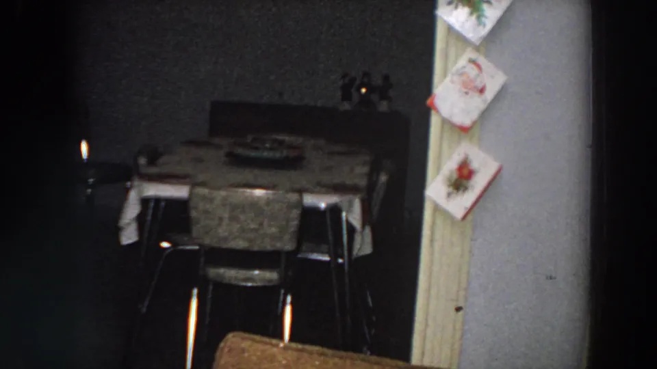 1958 Italian home interior with a small table, chairs, candles, and Christmas cards tacked near the doorway.