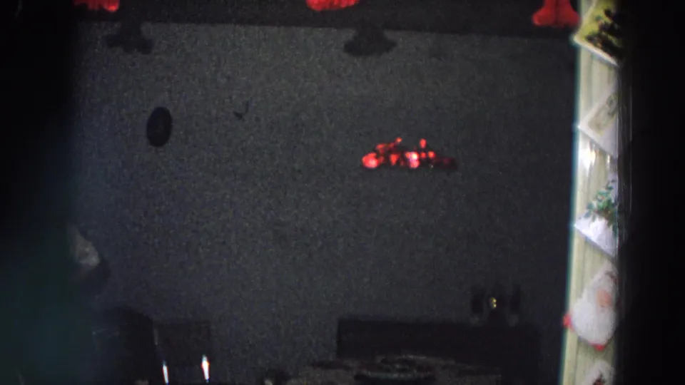 Dim 1958 Italy home interior with red tinsel on a dark wall and furniture edges partly visible.