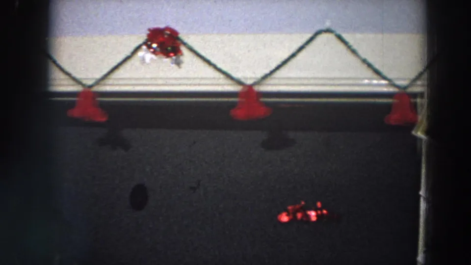 Dim 1958 Italy room detail with red hanging ornaments, tinsel, and dark wall surfaces below.