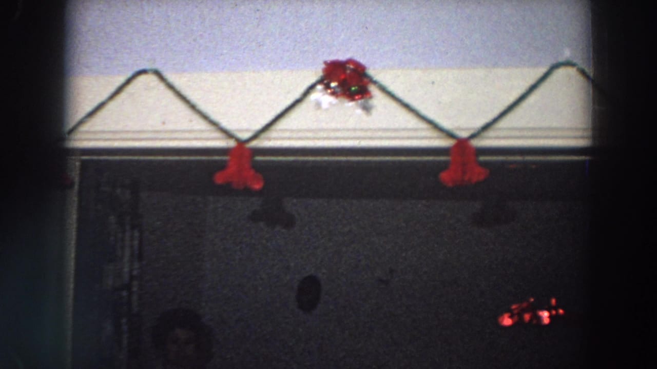 Red holiday garland and ornament above a dark doorway with part of a person faintly visible below.
