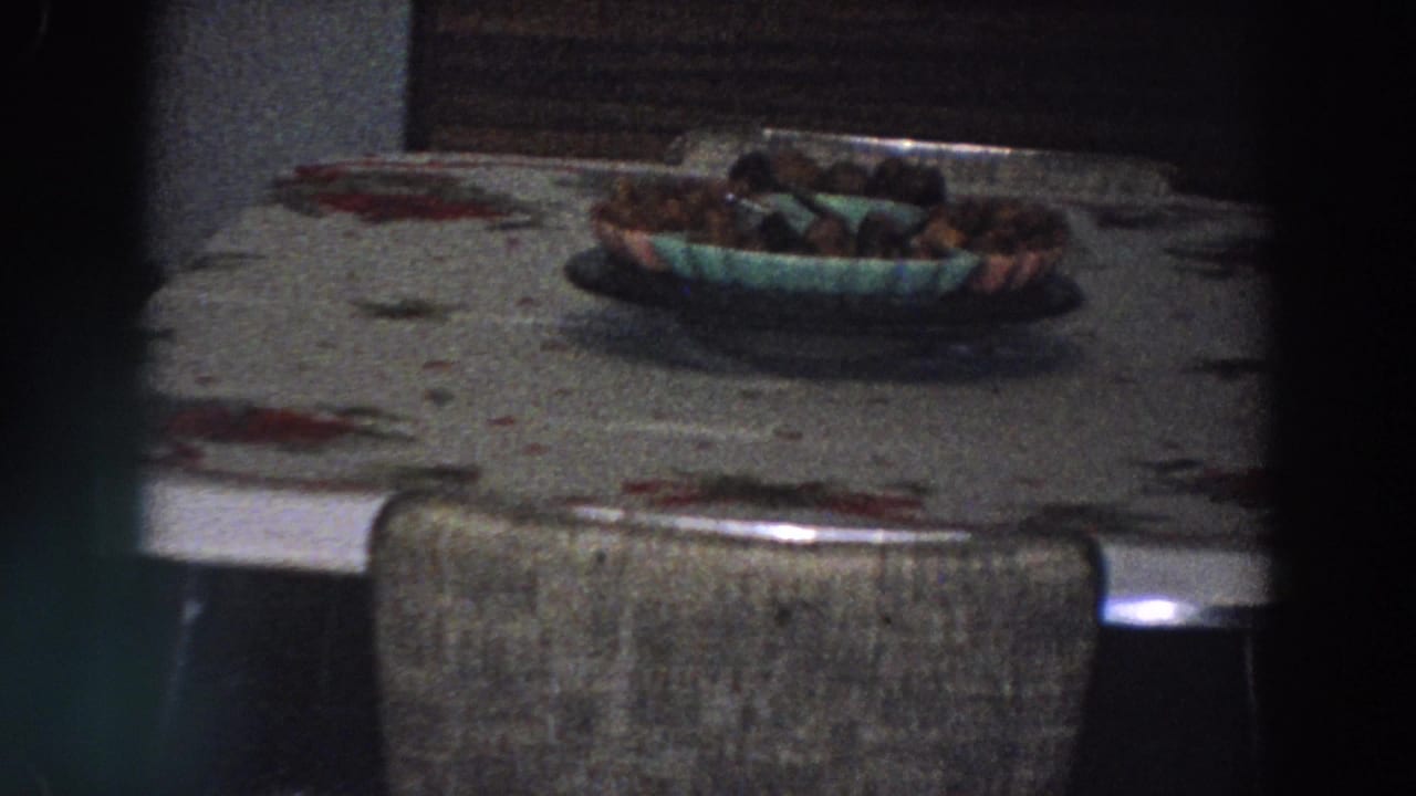 A dining table in the Italian home shows a floral tablecloth, upholstered chair, and bowl of food under low indoor light.