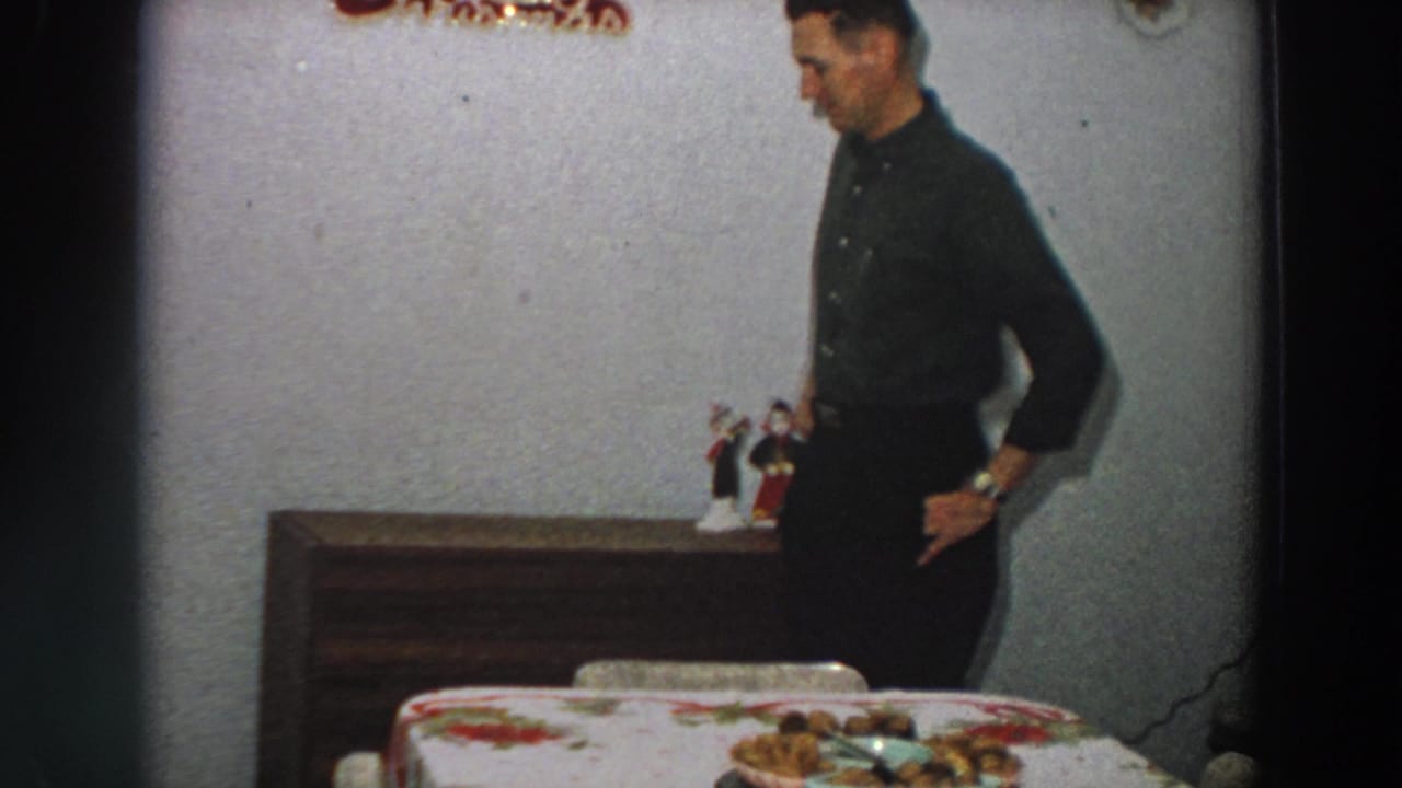The man looks down while standing beside the dining table in a private 1958 Italian home interior.