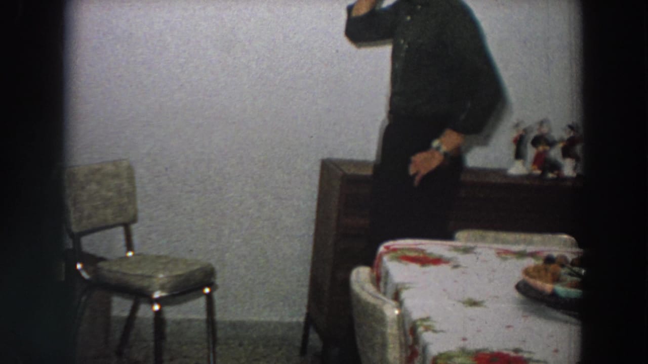 The man moves partly out of frame in the 1958 Italian dining room, with a chair, sideboard, figurines, and table visible.