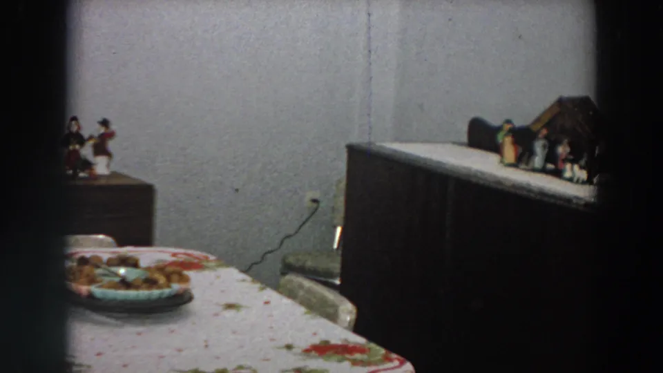 A 1958 Italian dining room view shows the table, food plate, wooden furniture, wall outlet, and small household decorations.