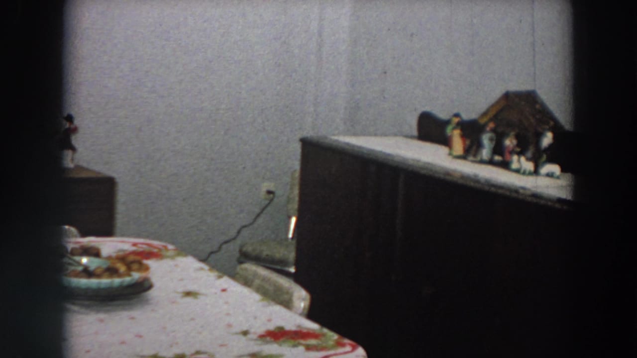 Dim room with floral tablecloth, dark cabinet, and small nativity scene on top.