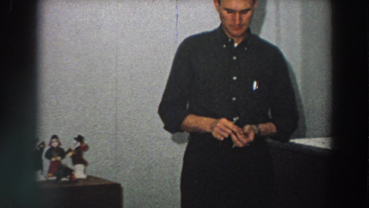 The closing frame shows the man still holding the small box in the 1958 Italian home interior, with figurines and furniture at left.