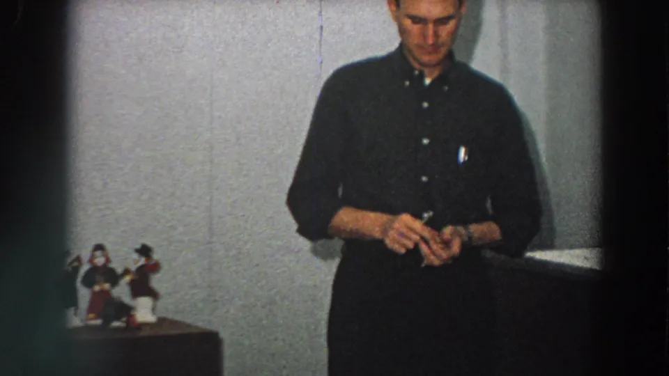 The closing frame shows the man still holding the small box in the 1958 Italian home interior, with figurines and furniture at left.